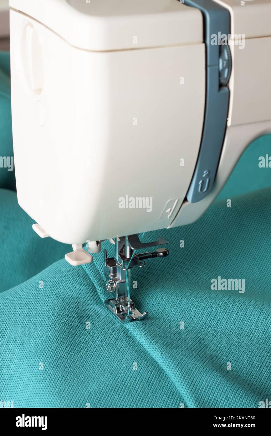 Modern sewing machine working with turquoise fabric. Sewing process