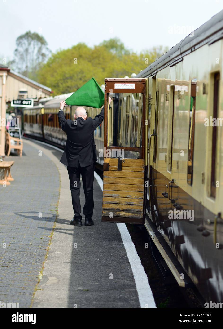 The guard is waving a green flag to the engine crew to signal the train