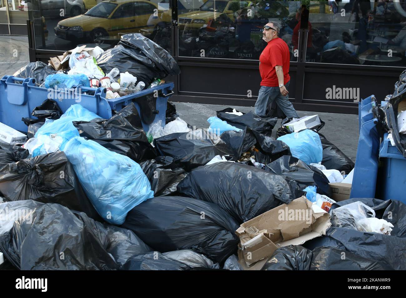 A man pases in front of garbage at Omonia square, down town Athens on June 23, 2017. Piles of rubbish accumulate around overflowing bins in Athens, in the wake of repeated strikes called by the Federation of workers in municipalities demanding the permanent hiring of about 10,000 contract workers whose contracts have expired (Photo by Panayotis Tzamaros/NurPhoto) *** Please Use Credit from Credit Field *** Stock Photo