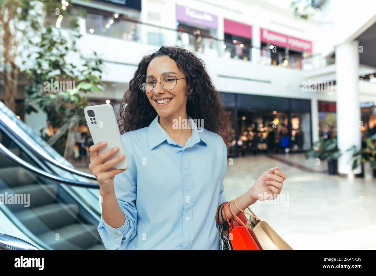 Happy hispanic woman in supermarket shopping, reading online message