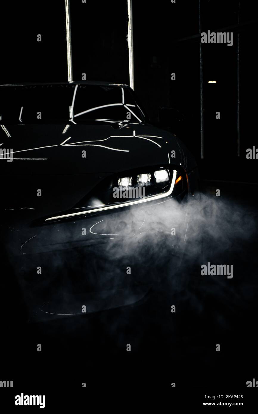 A vertical shot of Toyota Supra Mk5 headlights in the dark and fog