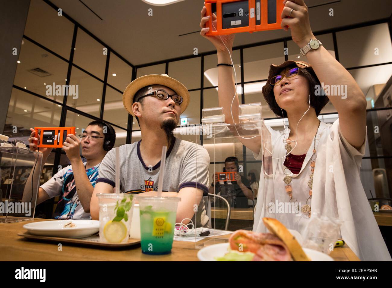 SENDAI, JAPAN - JULY 8: Anime fans holding a smart phone equipped with augmented reality (AR) application enjoying their virtual idol Hatsune Miku while having some sweets during an event in Sendai, Japan on July 8, 2017. As part of a promotion with telecommunications provider au/KDDI, Crypton Future Media and Blue Leaf Cafe operator, guest can enjoy dining with a special menu with their Vocaloid superstarIdol Hatsune Miku several days. (Photo by Richard Atrero de Guzman/NUR Photo) (Photo by Richard Atrero de Guzman/NurPhoto) *** Please Use Credit from Credit Field *** Stock Photo