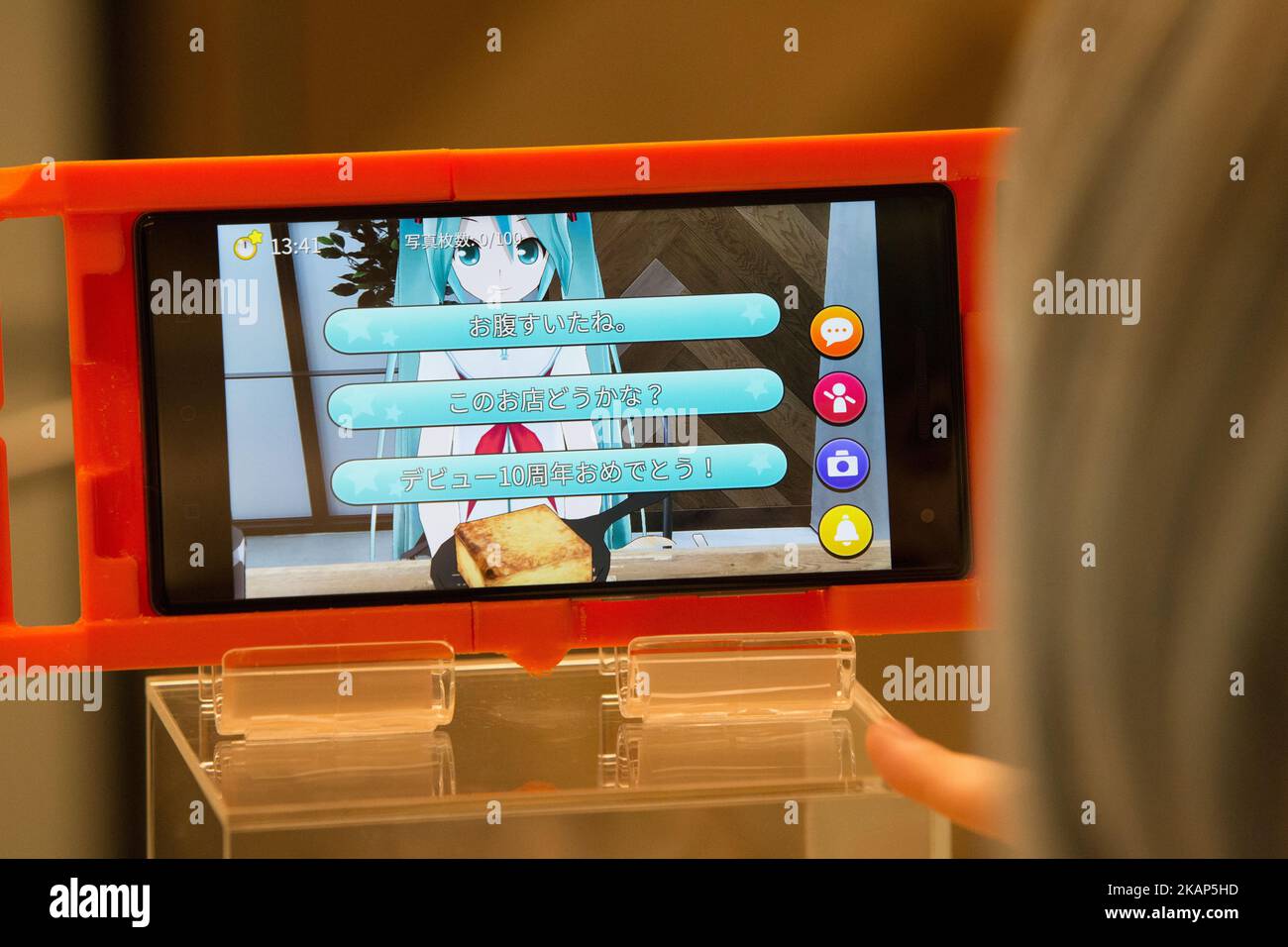 SENDAI, JAPAN - JULY 8: Anime fan looking at menu of a smart phone equipped with augmented reality (AR) application enjoying his virtual idol Hatsune Miku while having some sweets during an event in Sendai, Japan on July 8, 2017. As part of a promotion with telecommunications provider au/KDDI, Crypton Future Media and Blue Leaf Cafe operator, guest can enjoy dining with a special menu with their Vocaloid superstarIdol Hatsune Miku several days. (Photo by Richard Atrero de Guzman/NUR Photo) (Photo by Richard Atrero de Guzman/NurPhoto) *** Please Use Credit from Credit Field *** Stock Photo