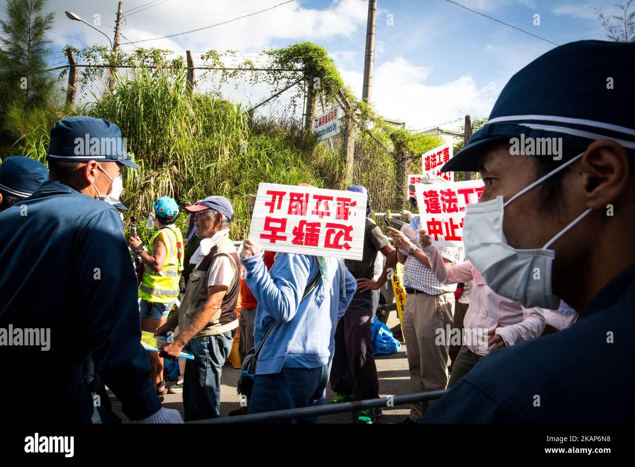 Anti-US base protesters were guarded by riot police as they try to block construction trucks in front of the Camp Schwab gate to protest against the construction of the new U.S Marine base on July 13, 2017 in Henoko, Nago, Okinawa prefecture, Japan. Around 52 construction vehicles loaded with stones and heavy equipment entered the US Marine base today to continue constructing the new US Marine Base. Over the next five years, a new facility will be built in the waters off the coast from Camp Schwab as part of the relocation of the Futenma Air Station to the Henoko area on the island of Okinawa. Stock Photo