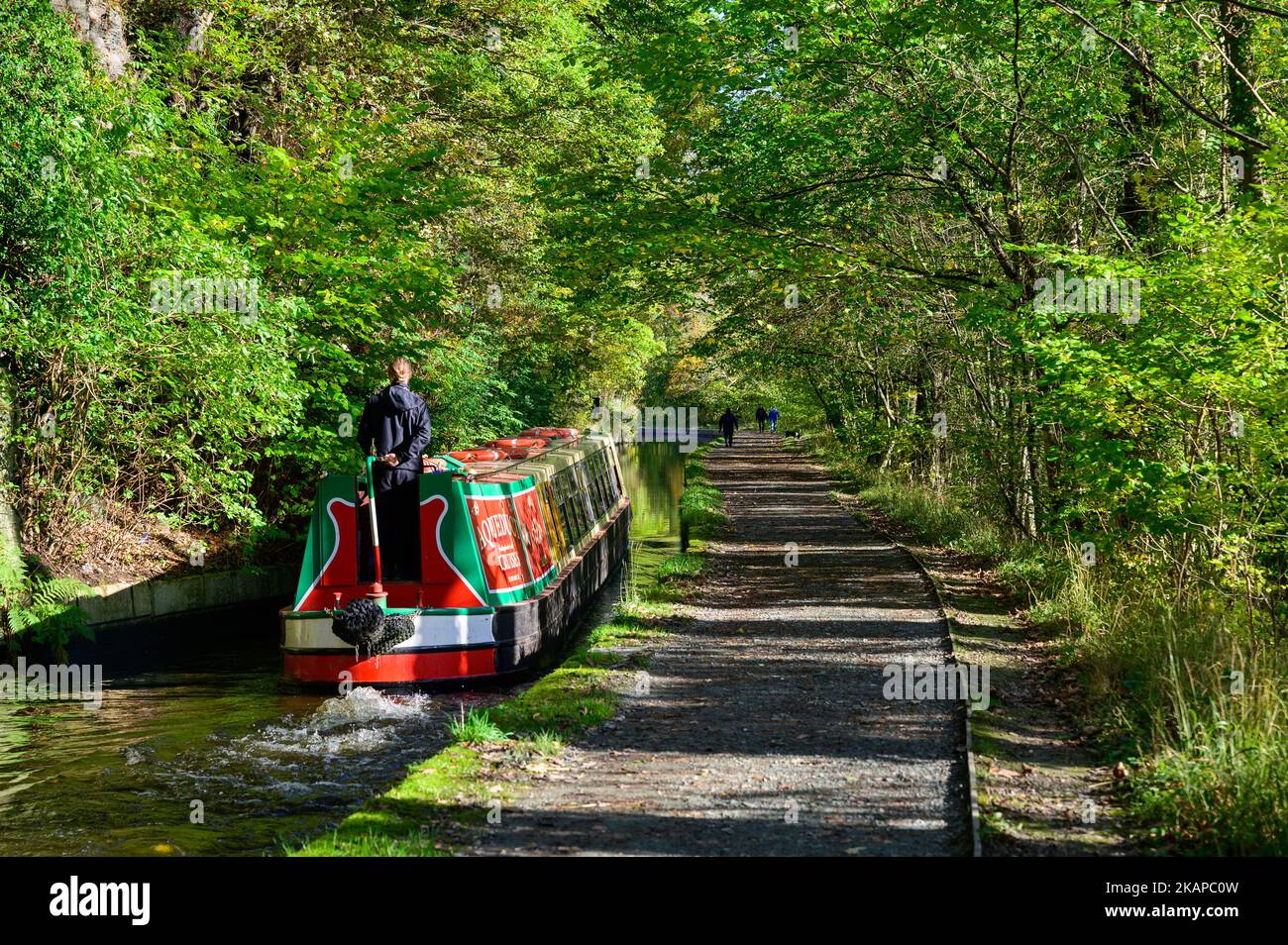 People enjoying a trip on a narrowboat in the late autumn sunshine on the Llangollen Canal in Clwyd, Wales Even in early November many of the leaves are yet to turn colour. Stock Photo