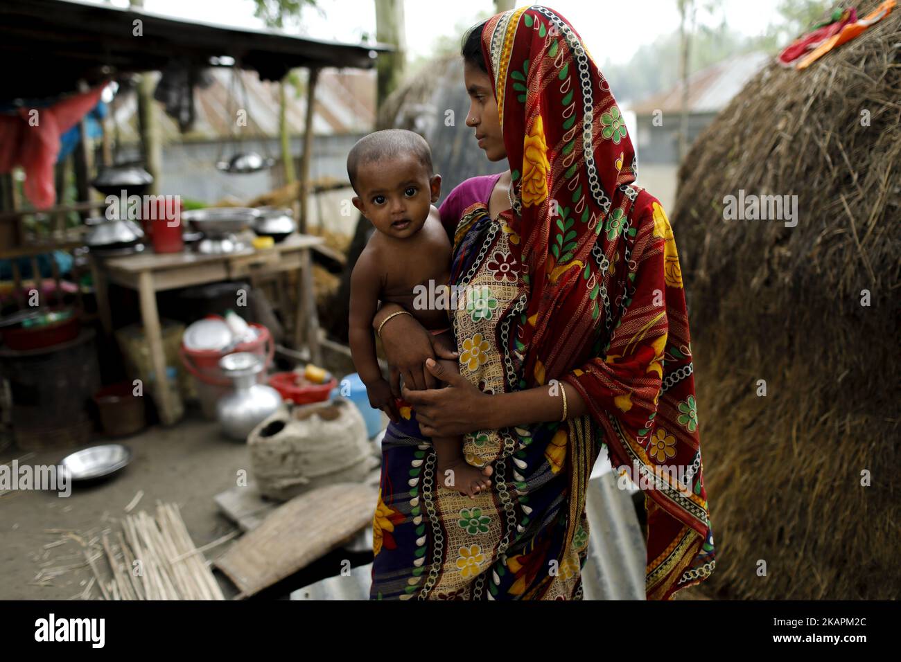 A woman with her son moves to other place for continuous flooding in Sariakandhi area at Bogra, Bangladesh on August 16, 2017. Peoples’ suffering continues as many of them left their homes along with their cattle, goats, hens and other pets and took shelter in safe areas and many of these people have still not been able to return as water has not fully receded from their homes. Flood-related incidents in Dinajpur, Gaibandha and Lalmonirhat raising the death toll to 30 in the last three days across the country. (Photo by KM Asad/NurPhoto) Stock Photo