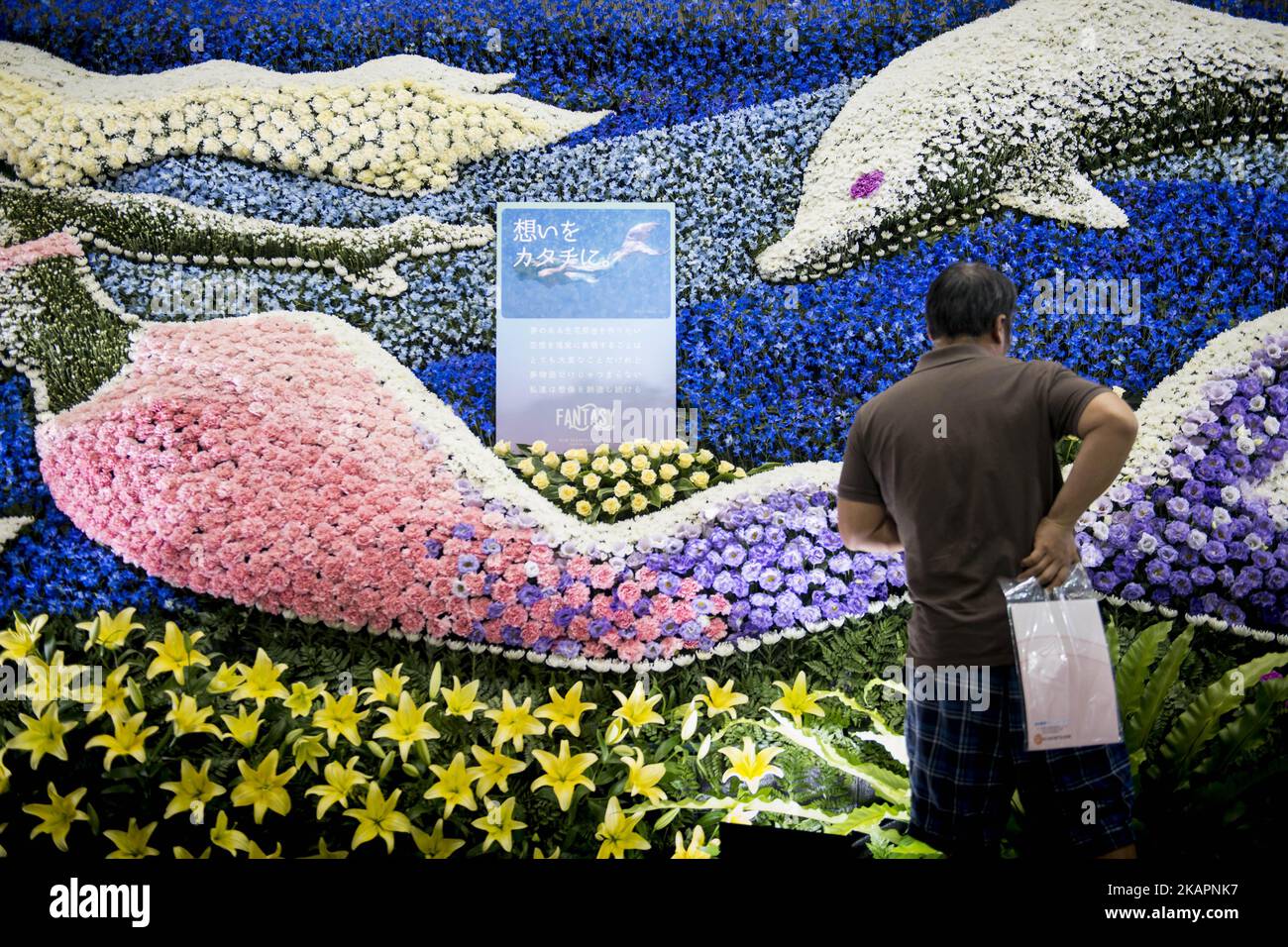 Visitor to the Tokyo Int'l Funeral & Cemetery Show look at a wall of flowers, in Tokyo, Japan on August 23, 2017. Hundreds of funeral home operators, cemeteries operators, crematorium operators, traders, suppliers, buyers, professional associations and investors gather at this professional funeral event. (Photo by Alessandro Di Ciommo/NurPhoto) Stock Photo
