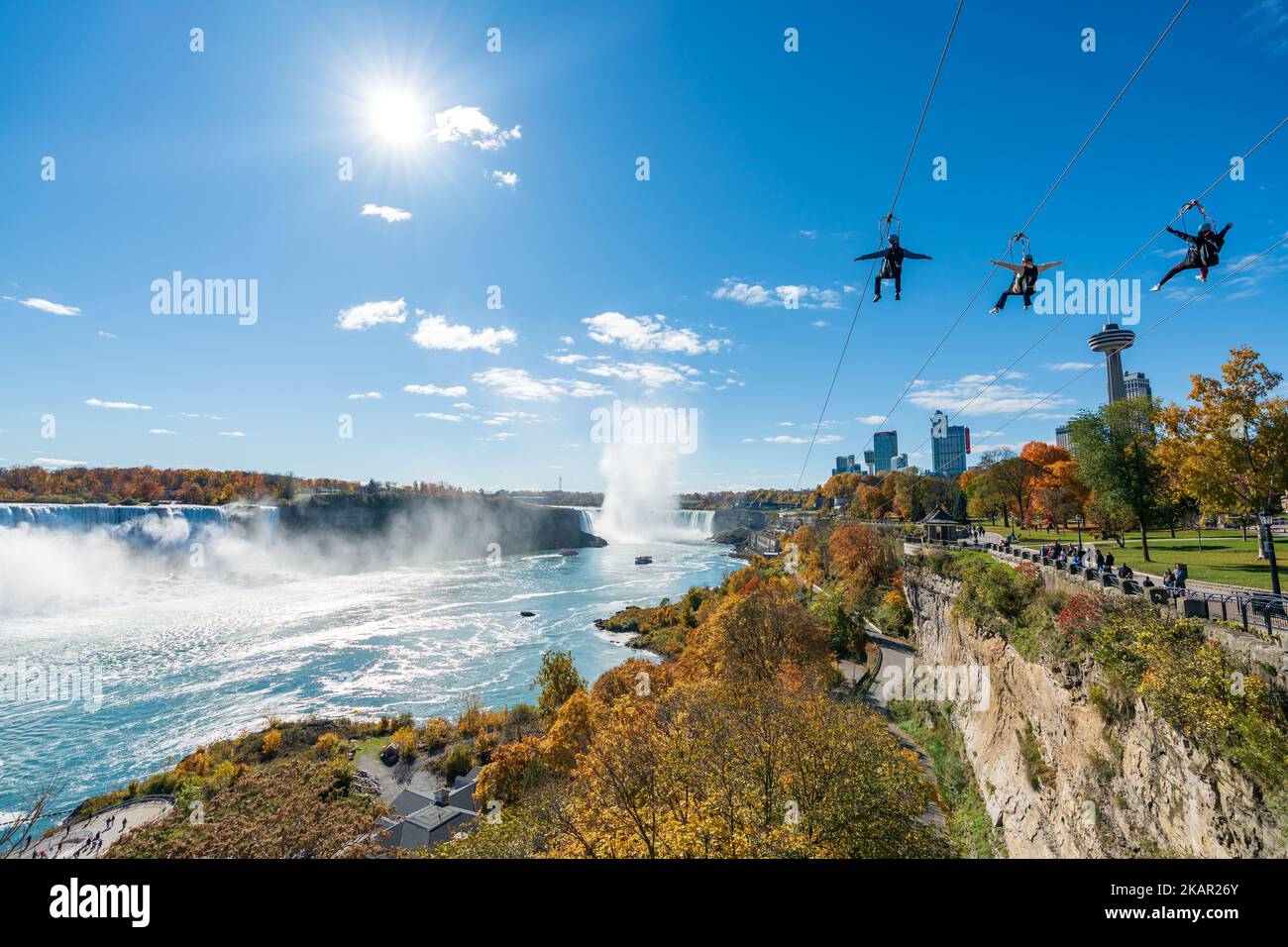 People using the Niagara Falls Zipline ride attraction. Niagara Falls City Red maple leaf during autumn foliage. Ontario, Canada. Stock Photo