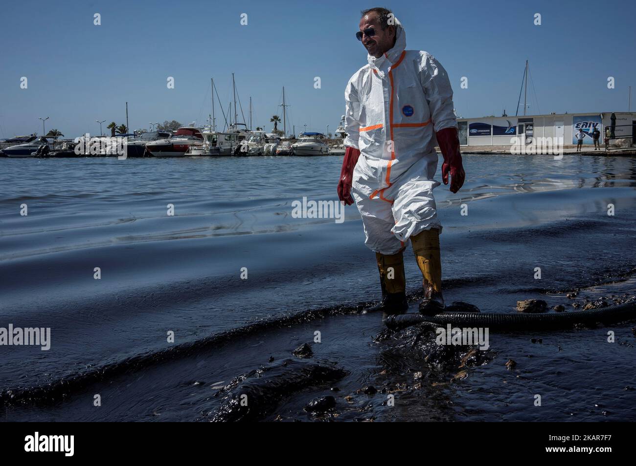 A municipal worker tries to contain the oil spill from the Greek tanker Agia Zoni II, which sank off the island of Salamis, on one of the beaches of the Athens riviera. Athens, September 14, 2017. The small tanker 'Agia Zoni II' sank on September 10, whilst anchored off the coast of Salamis, near Greece's main port of Piraeus. It was carrying a cargo of 2,200 tons of fuel oil and 370 tons of marine gas oil. Salamis Island has suffered heavy pollution as a result in what has been called a 'major environmental disaster' by officials. (Photo by Kostis Ntantamis/NurPhoto) Stock Photo