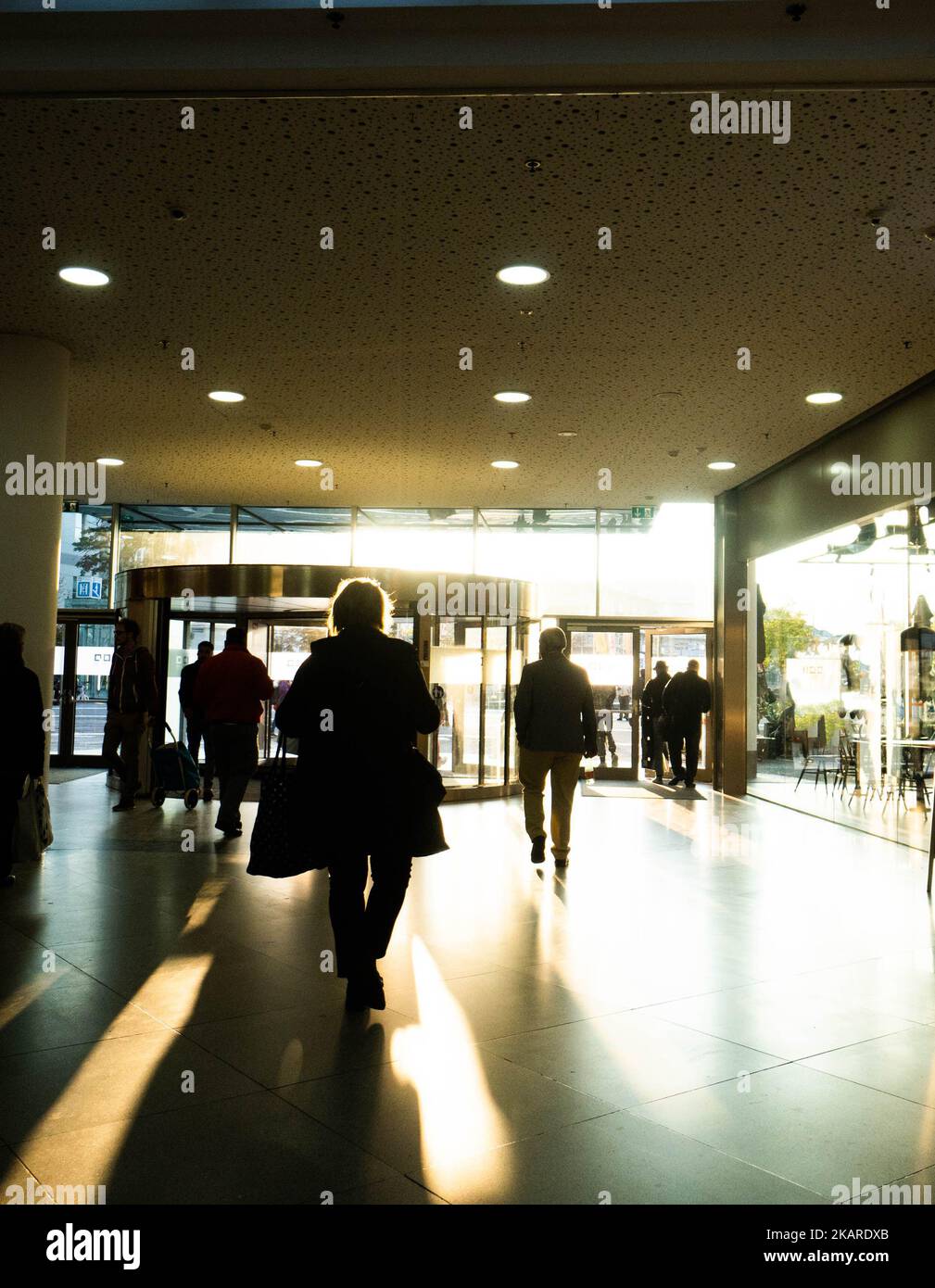 people going in and out of the mall with the sun shining Stock Photo