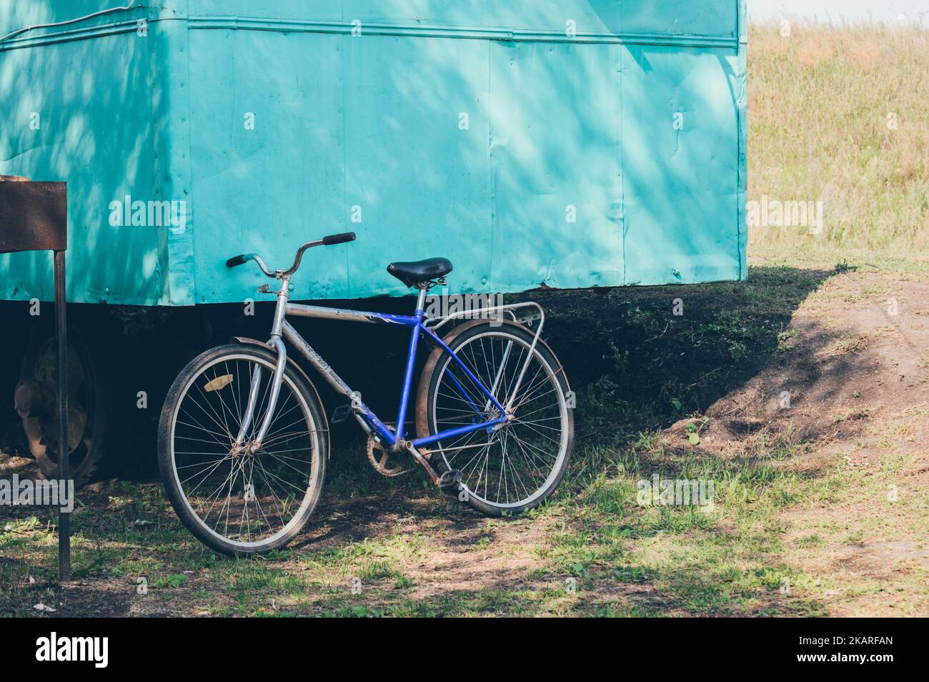 Bike parked near green work trailer in shadow Stock Photo
