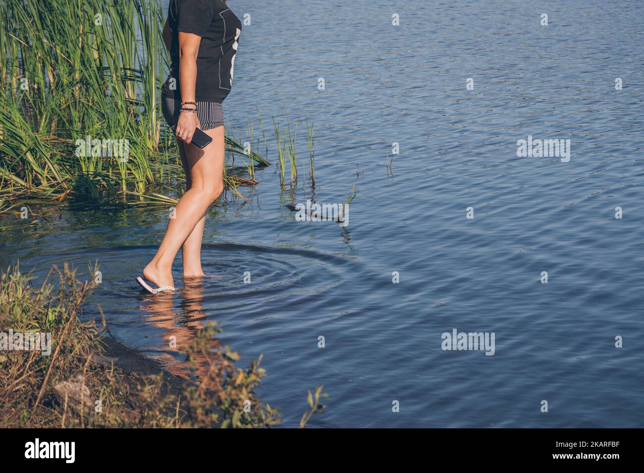 Legs of girl in shorts entering river, circles on water Stock Photo