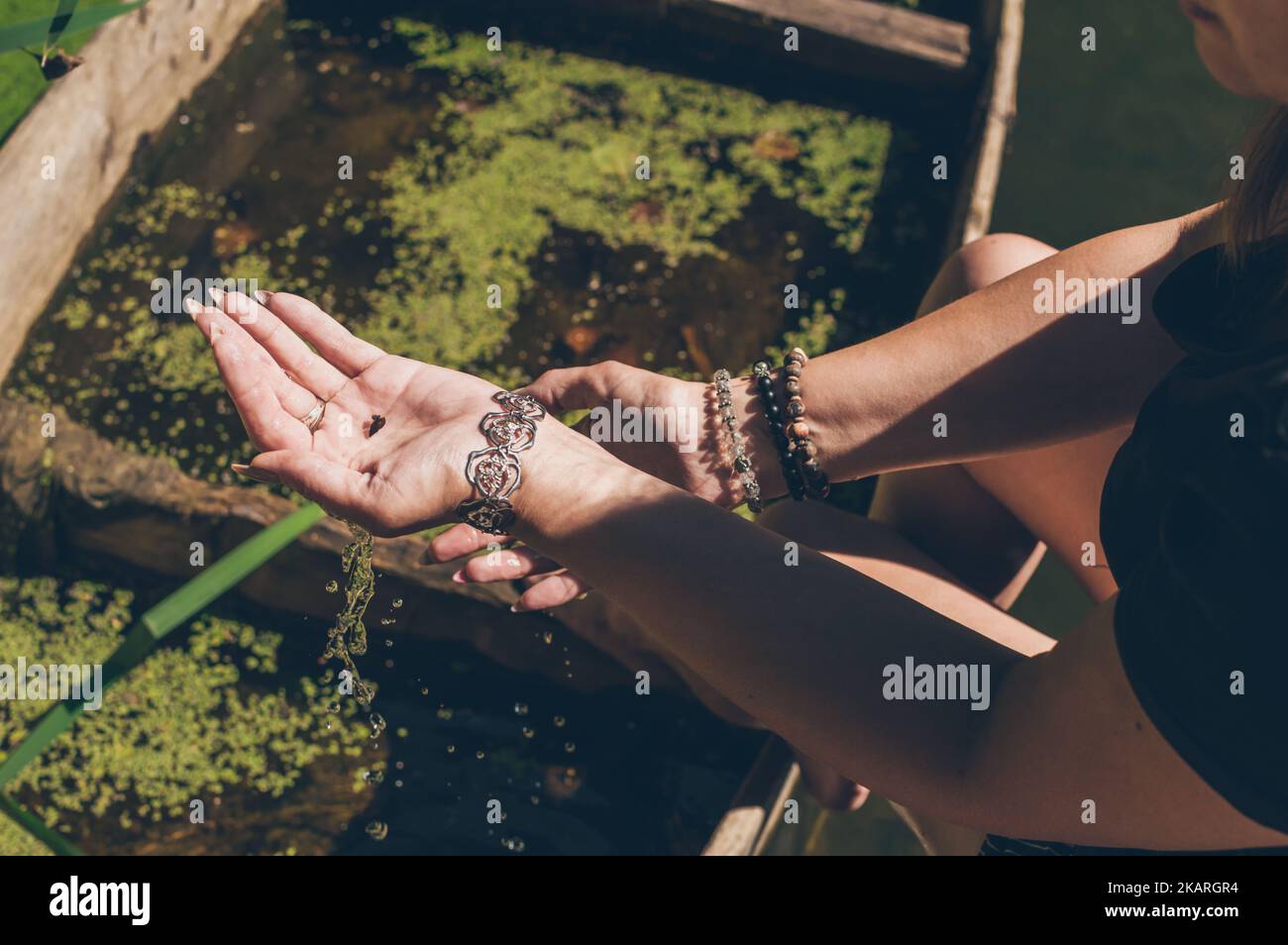 Little snail in woman's hands with bracelets in sunlight Stock Photo