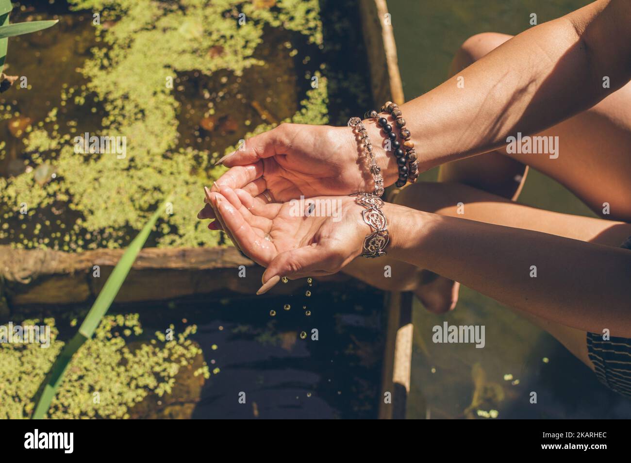 Little snail in woman's hands with bracelets in sunlight Stock Photo