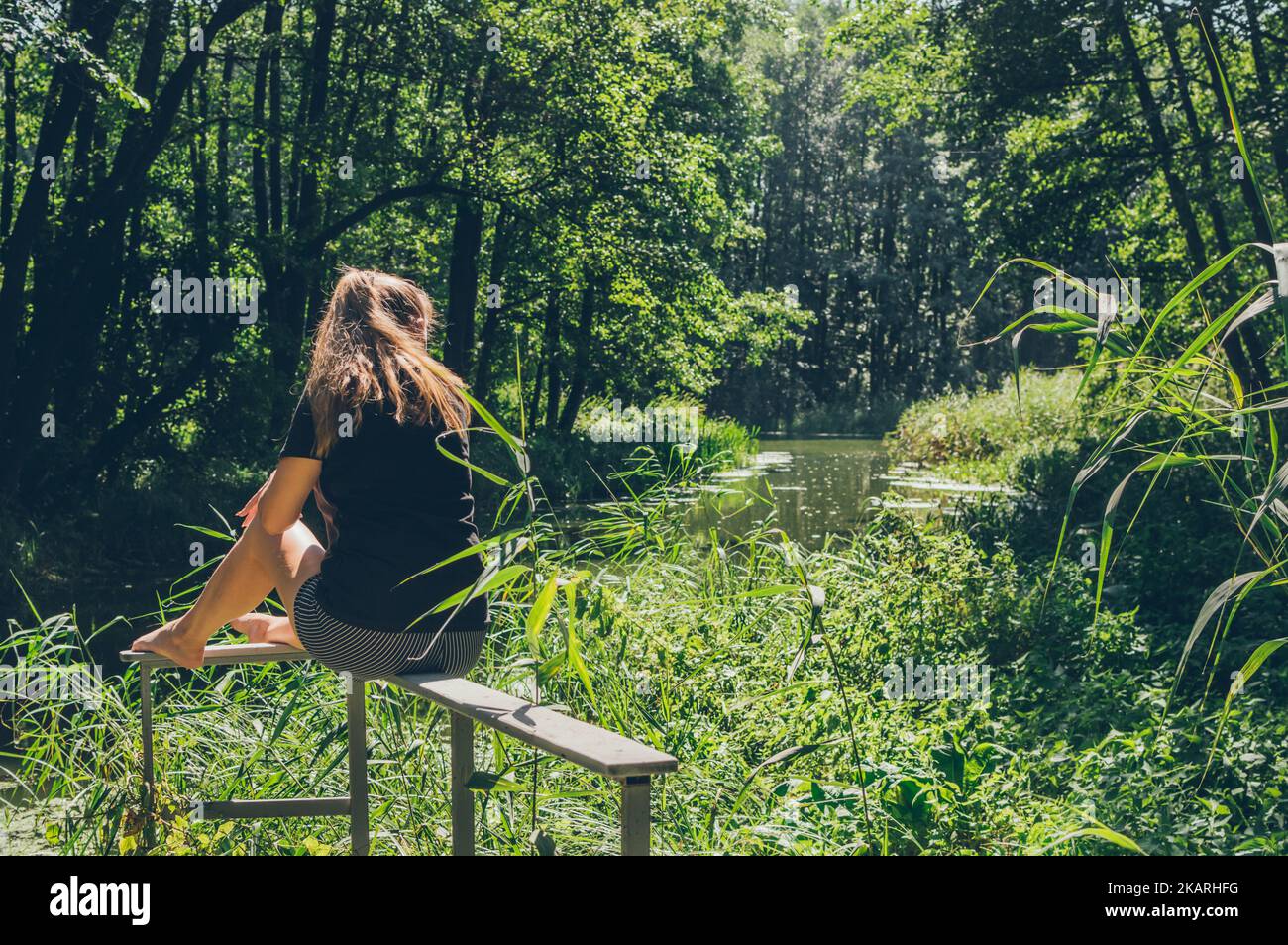 Woman sitting and enjoying sun and forest landscape Stock Photo
