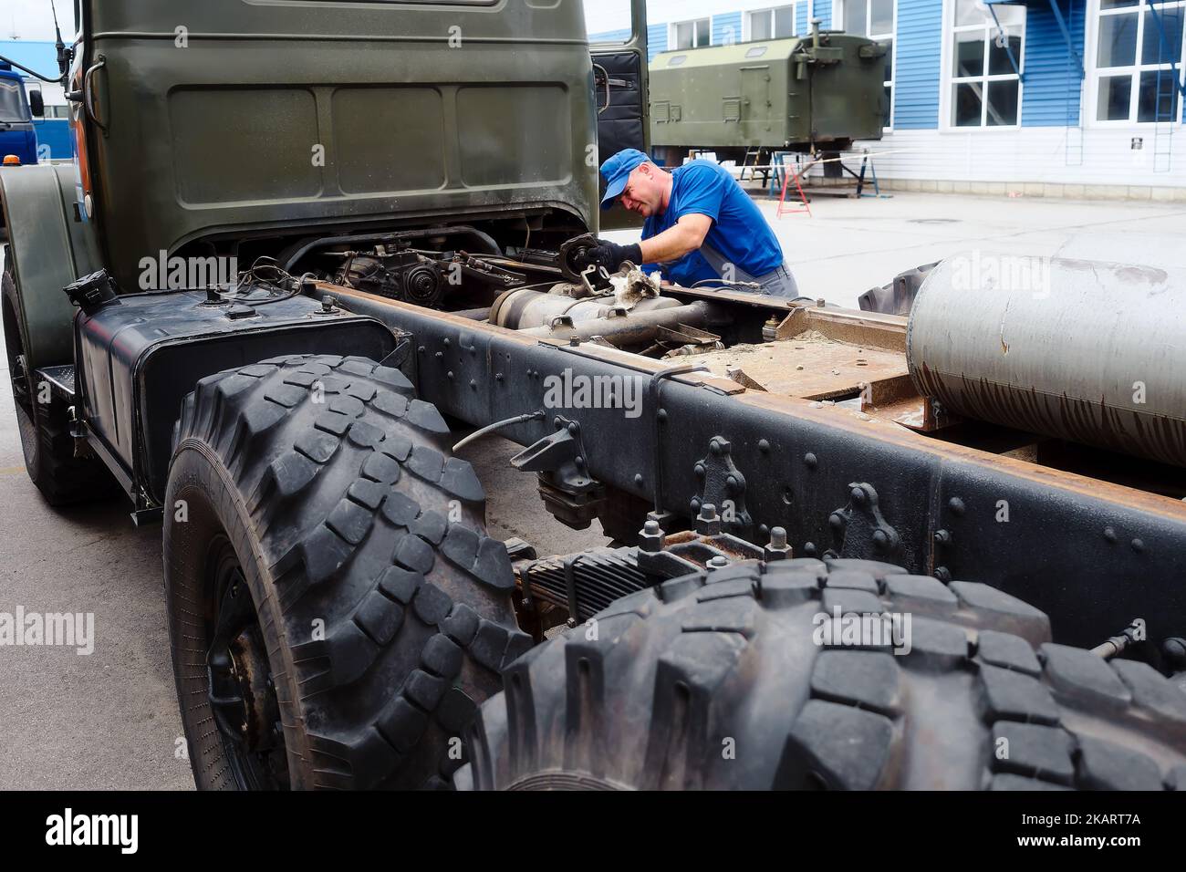 Mechanic in overalls repairs truck on summer day outside. Urgent repair of trucks. Authentic workflow.. Stock Photo