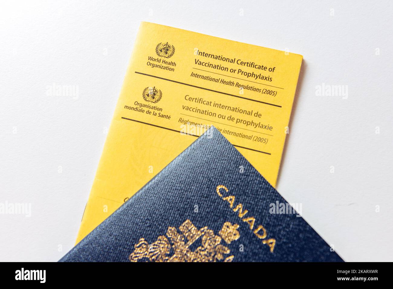 A blue Canadian Passport on a World Health Organisation Vaccine Passport Stock Photo