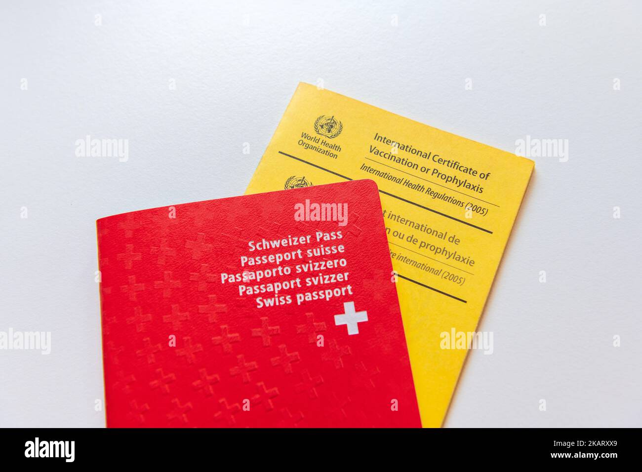 A red Swiss Passport on a World Health Organisation Vaccine Passport Stock Photo