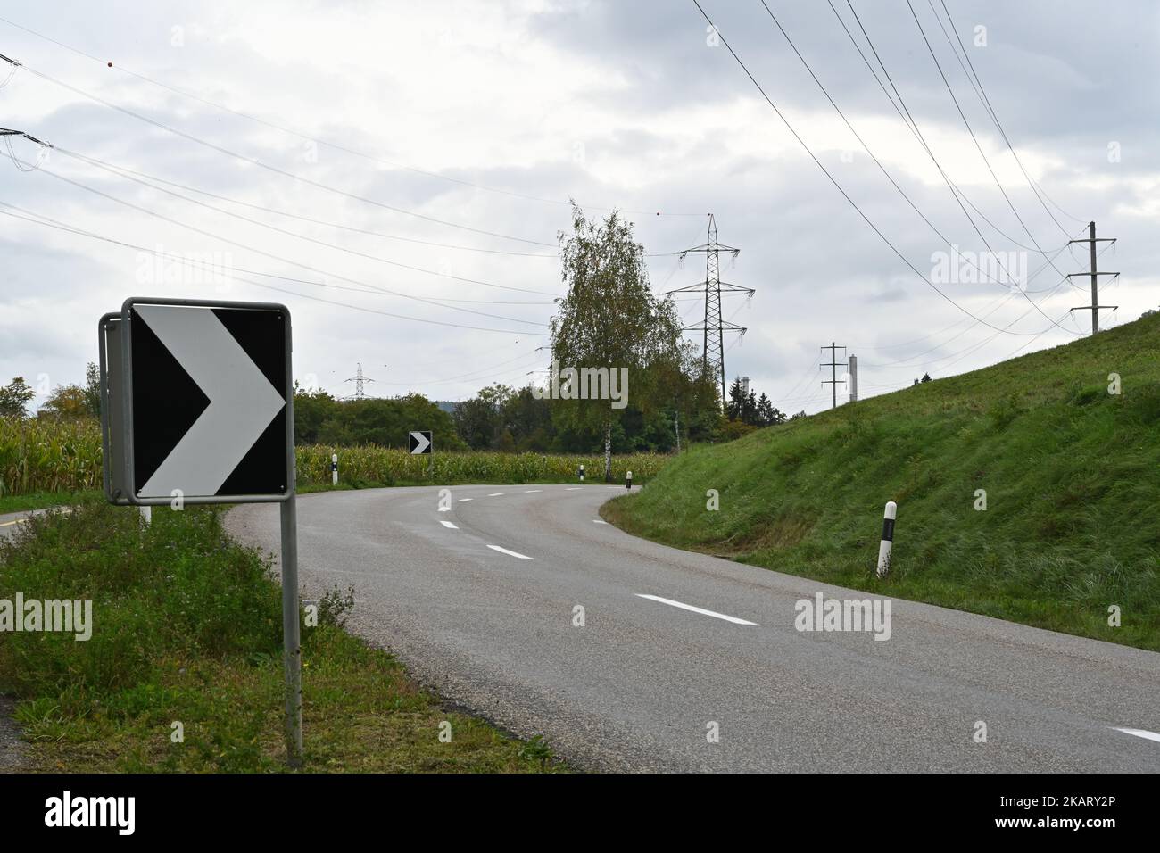 Warning black and white arrow traffic sign on sharp, dangerous road bend in a mountainous area. Stock Photo