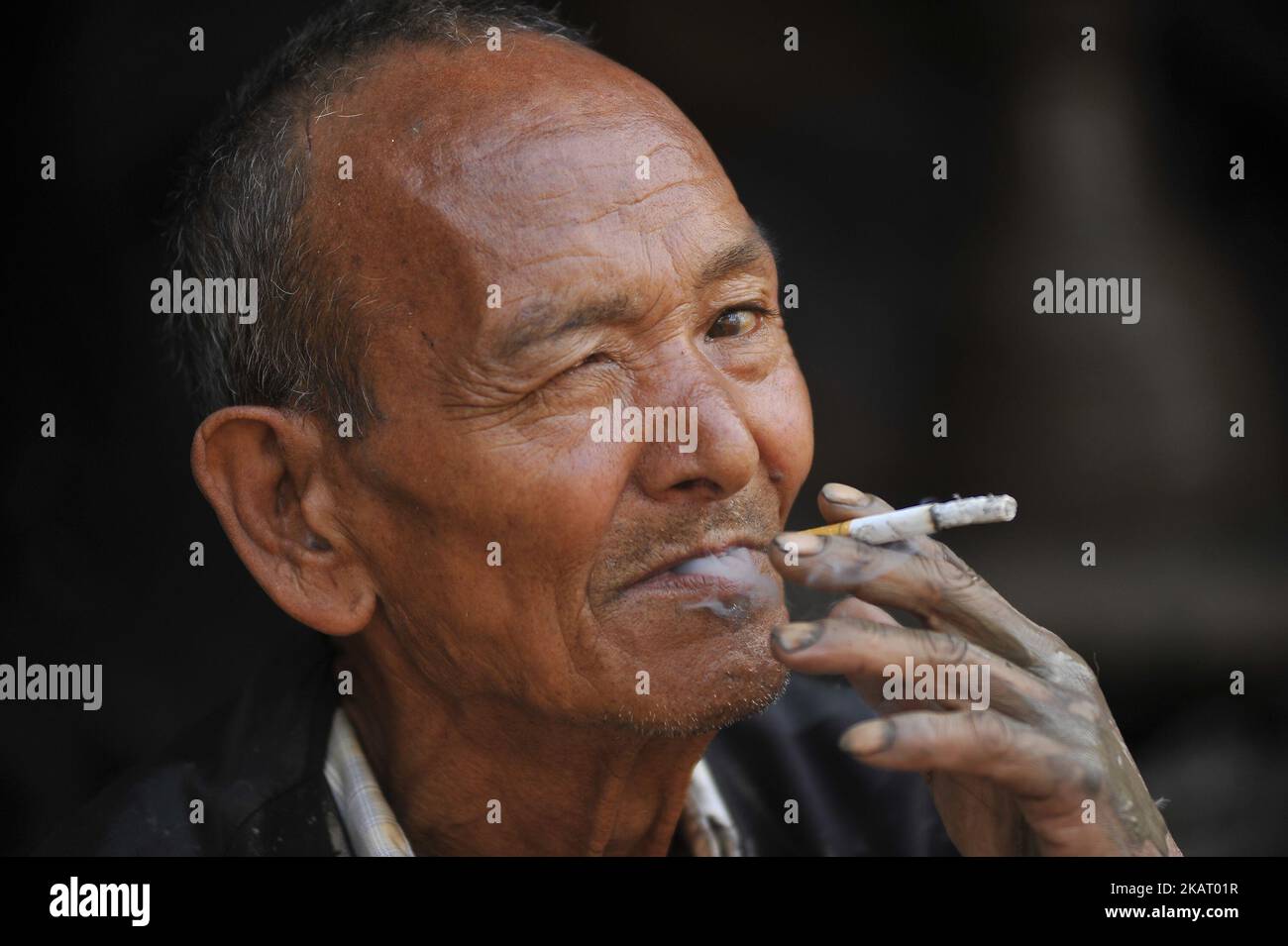 74yrs old GANESH BHAKTA PRAJAPATI, takes rest by smoking cigarette after making clay pot lamps for upcoming Tihar or Deepawali Festival on his workshop at Pottery Square, Bhaktapur, Nepal on Monday, October 16, 2017. Nepalese Potter works on their small scale traditional pottery making industry in Bhaktapur, Nepal. Bhaktapur is an ancient town in the Kathmandu Valley and is listed as a World Heritage Site by UNESCO for its rich culture, temples, and wood, metal and stone artwork. (Photo by Narayan Maharjan/NurPhoto) Stock Photo