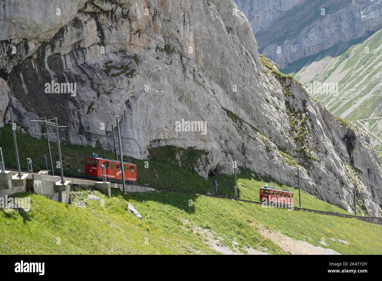 Two red cogwheel trains between railway station Alpnachstad and mountain Pilatus Kulm. Stock Photo