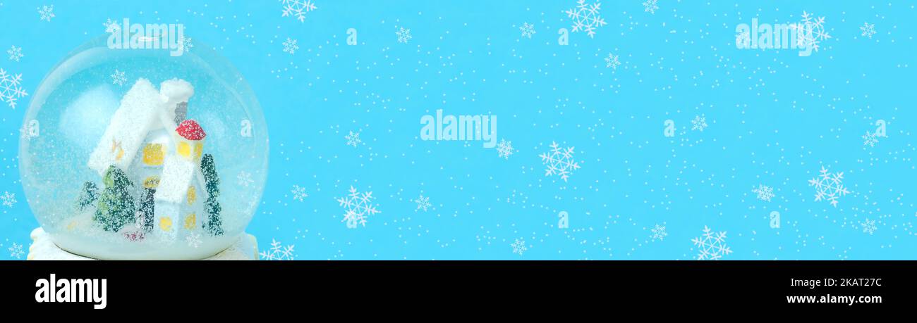 Blue christmas background baner with snow globe with house and fir trees with snowflakes with copy space. Stock Photo