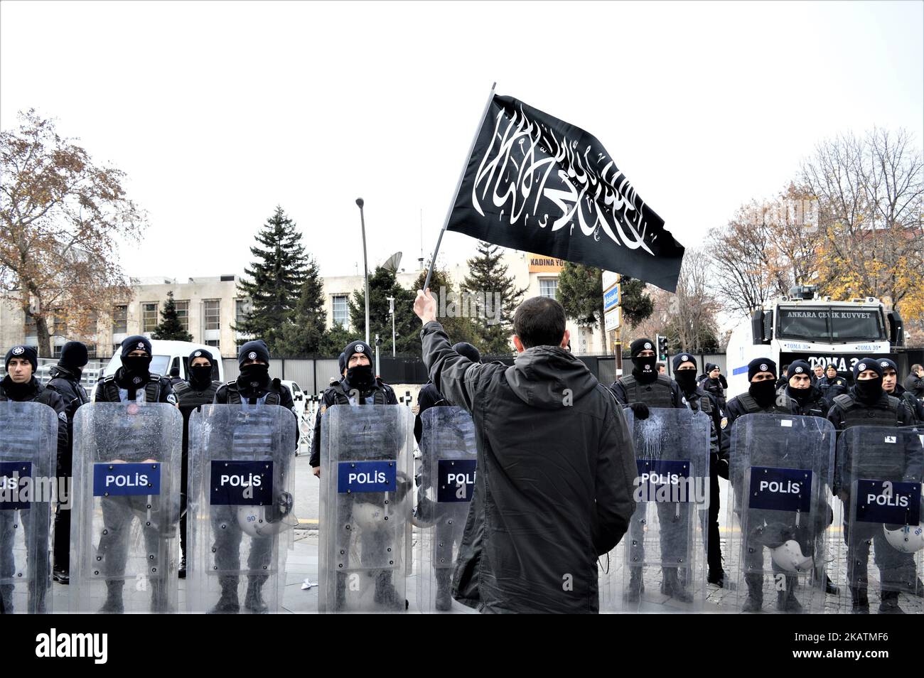 A photo taken in Ankara, Turkey on December 7, 2017 shows a protester waving a black flag with Arabic letters in front of Turkish riot policemen as Turkish Muslims take part in a protest near the U.S. Embassy against its president Donald Trump's officially recognition the city of Jerusalem as the capital of Israel on December 6. (Photo by Altan Gocher/NurPhoto) Stock Photo