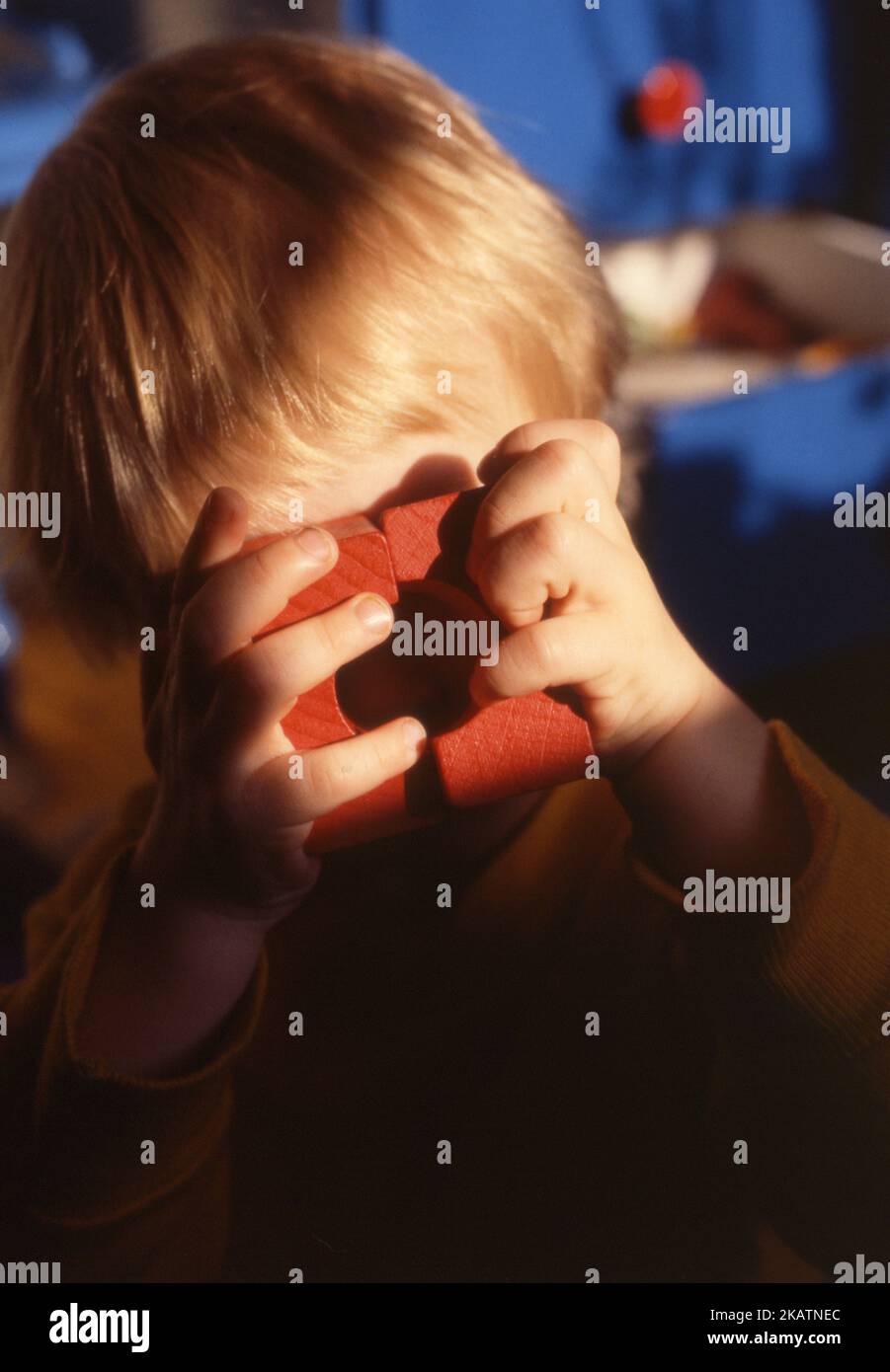 2 year child looking through wooden toy Stock Photo