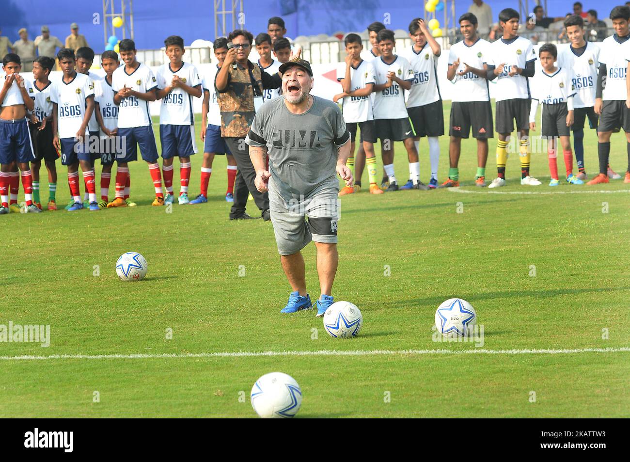 Argentina's soccer legend Diego Maradona kicks a football, gestures during a football workshop with school students in Barasat, around 38 Km north of Kolkata on December 12, 2017. Maradona is on a private visit to India.Diego Armando Maradona was born on 30 October 1960.During his time with the Argentina national team, Maradona scored 34 goals in 91 appearances. He made his full international debut at age 16, against Hungary, on 27 February 1977. Maradona was left off the Argentine squad for the 1978 World Cup on home soil by coach Cesar Luis Menotti who felt he was too young at age 17.Maradon Stock Photo