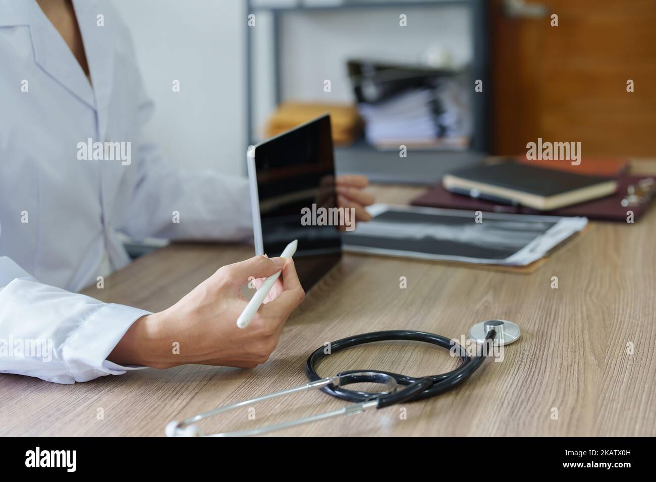An Asian female doctor shows the patient a computer tablet to see the ...