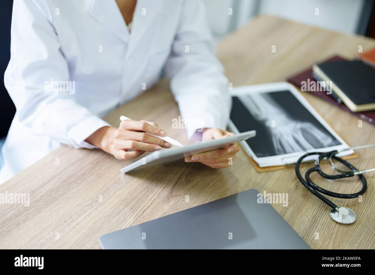 An Asian female doctor is using a tablet computer to analyze patient symptoms before treatment Stock Photo