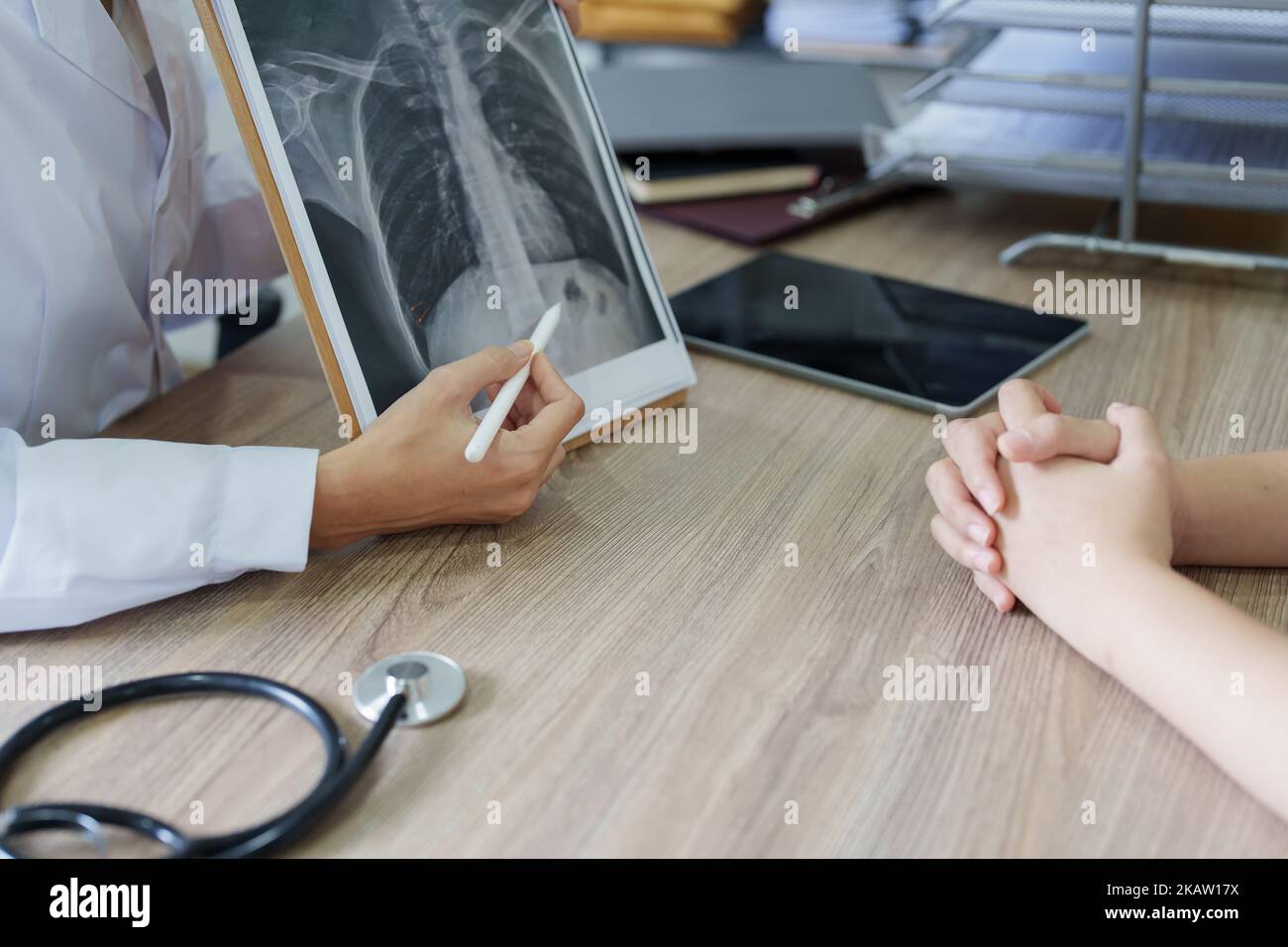 An Asian female doctor points to a patient xray film to explain the