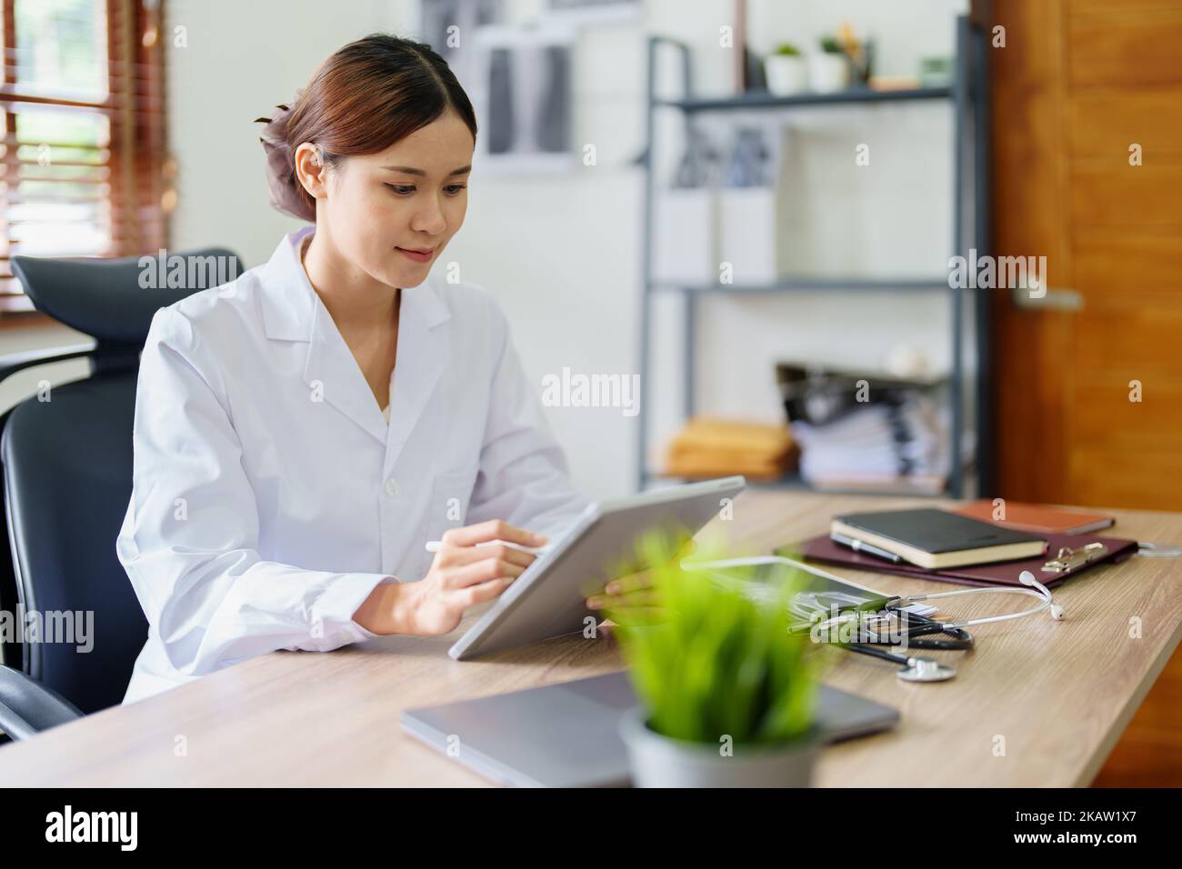 An Asian female doctor is using a tablet computer to analyze patient ...