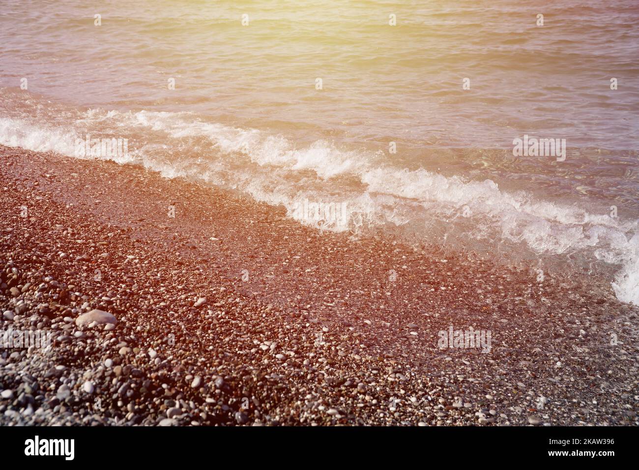 Bank of pebbles with the sea and beach in the background. Pebbles and water on the sea shore in Kemer, Antalya in Turkey Stock Photo