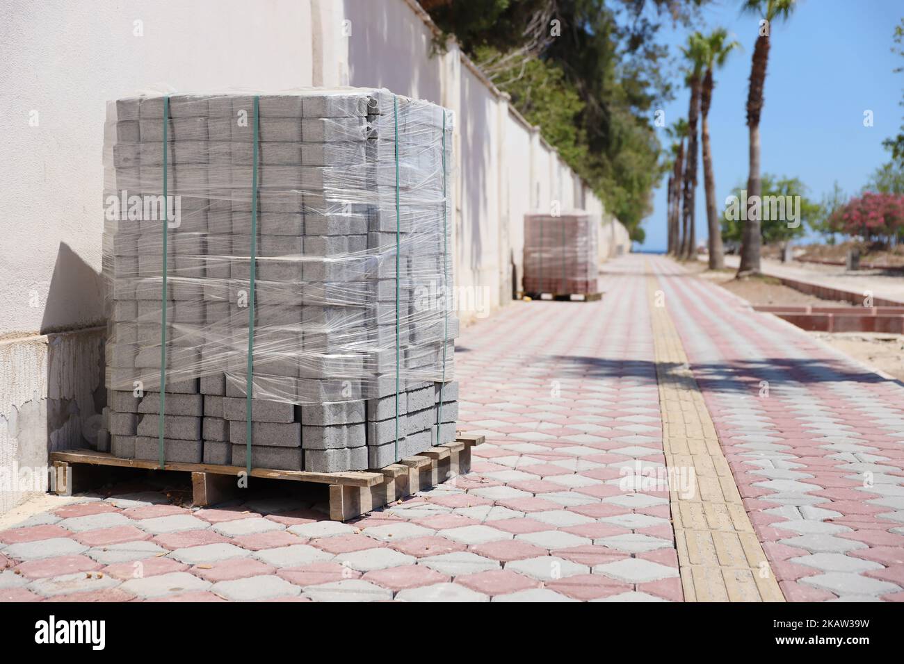 Paving stones on wooden pallet on the street sidewalk. Construction Paving of city streets and adjoining territories. Outdoor tile concrete paving blo Stock Photo
