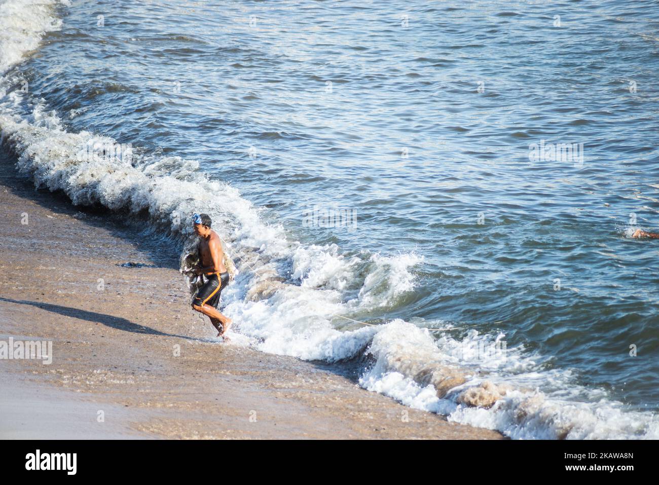 Salvador, Bahia, Brazil - November 01, 2021: Fisherman leaving the sea with fishing net at Rio Vermelho beach in Salvador, Bahia. Stock Photo