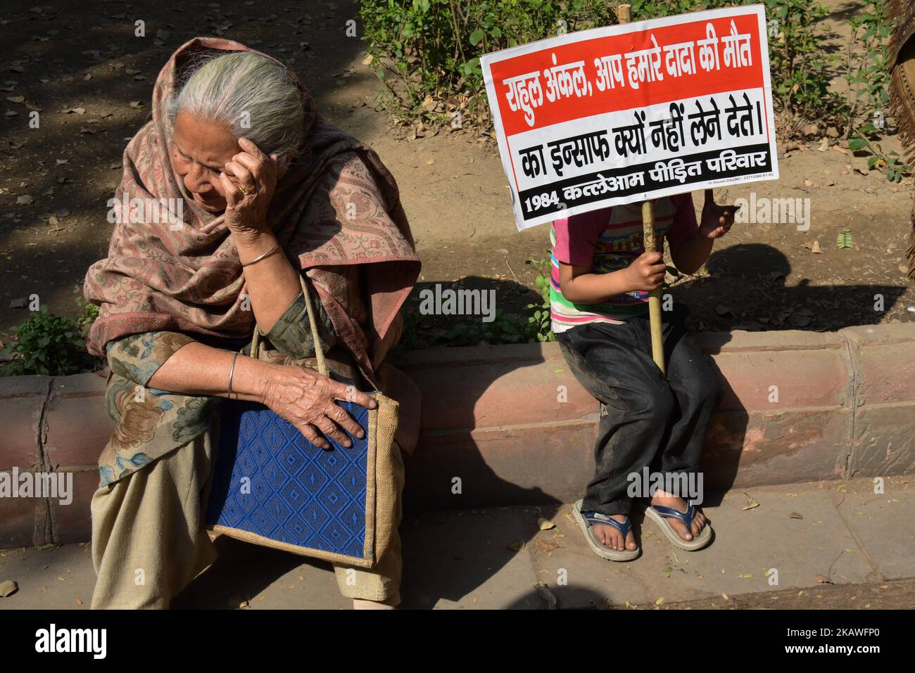 A young protestor sits holding a placard demanding justice from Indian National Congress Party President Rahul Gandhi along Akbar Road in New Delhi on 9th February, 2018. (Photo by Sahiba Chawdhary/NurPhoto) Stock Photo