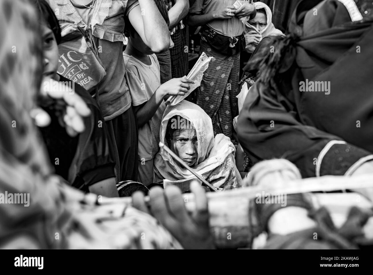 A Rohingya refugee woman and others wait to receive food aid from a local NGO at the Balukhali refugee camp near Cox's Bazar, Bangladesh, November 22, 2017. (Photo by Szymon Barylski/NurPhoto) Stock Photo