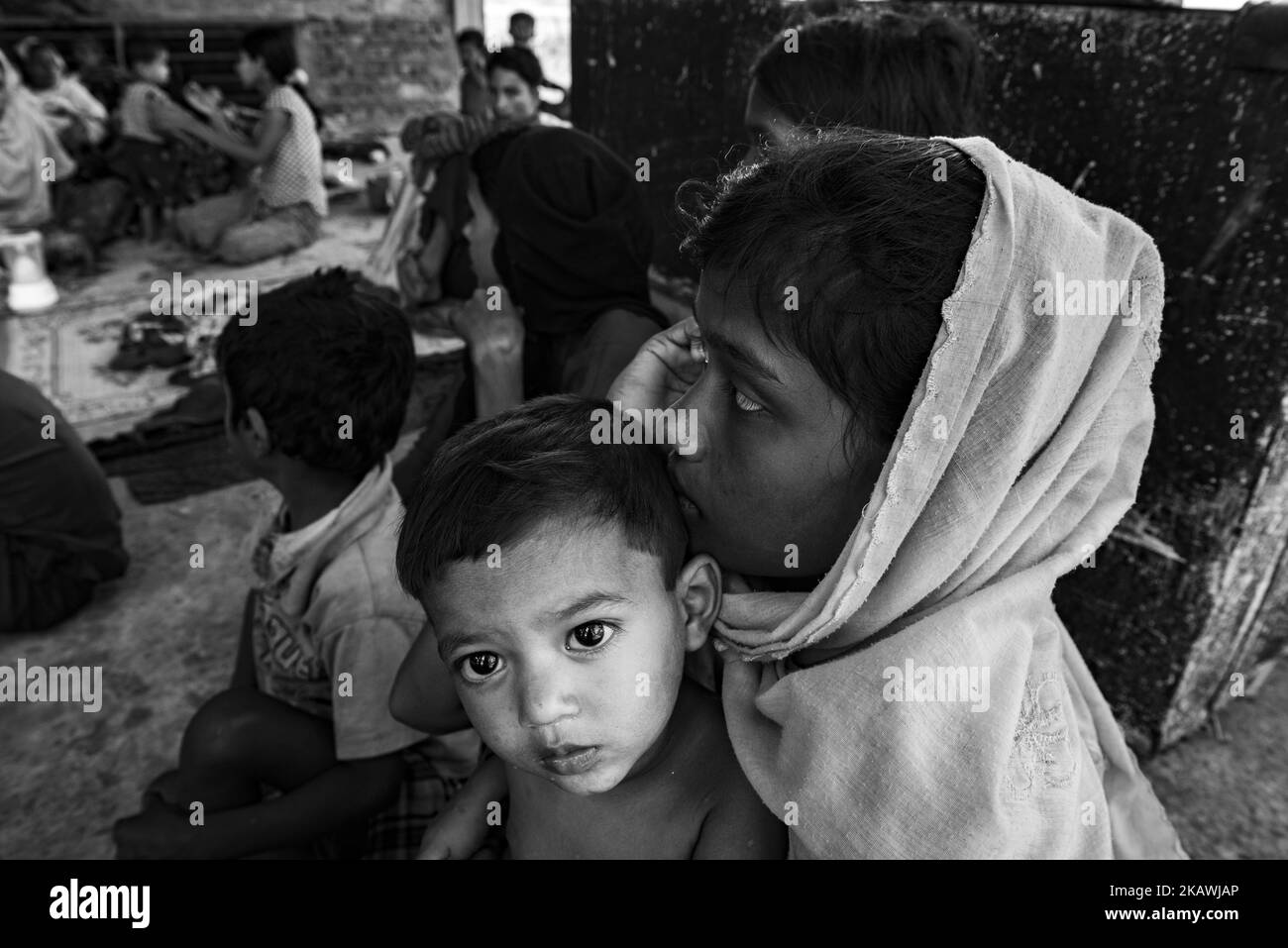 Rohingya refugee boy with his mother rest in temporary shelter after arriving by boat to Shah Porir Dwip near Cox's Bazar, Bangladesh, November 23, 2017. (Photo by Szymon Barylski/NurPhoto) Stock Photo