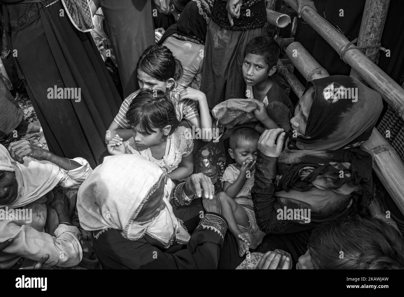 A Rohingya refugee woman and others wait to receive food aid from a local NGO at the Balukhali refugee camp near Cox's Bazar, Bangladesh, November 22, 2017. (Photo by Szymon Barylski/NurPhoto) Stock Photo