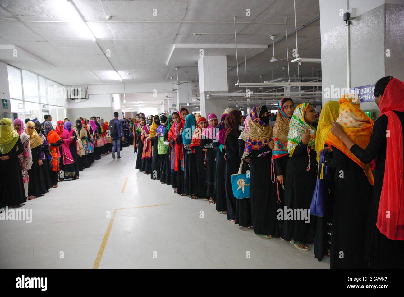 Bangladeshi female workers attend at their garments factory for work in Gazipur outskirts of Dhaka on February 17, 2018. The garment sector has provided employment opportunities to women from the rural areas that previously did not have any opportunity to be part of the formal workforce. This has given women the chance to be financially independent and have a voice in the family because now they contribute financially.However, women workers face problems. Most women come from low income families. Low wage of women workers and their compliance have enabled the industry to compete with the world Stock Photo