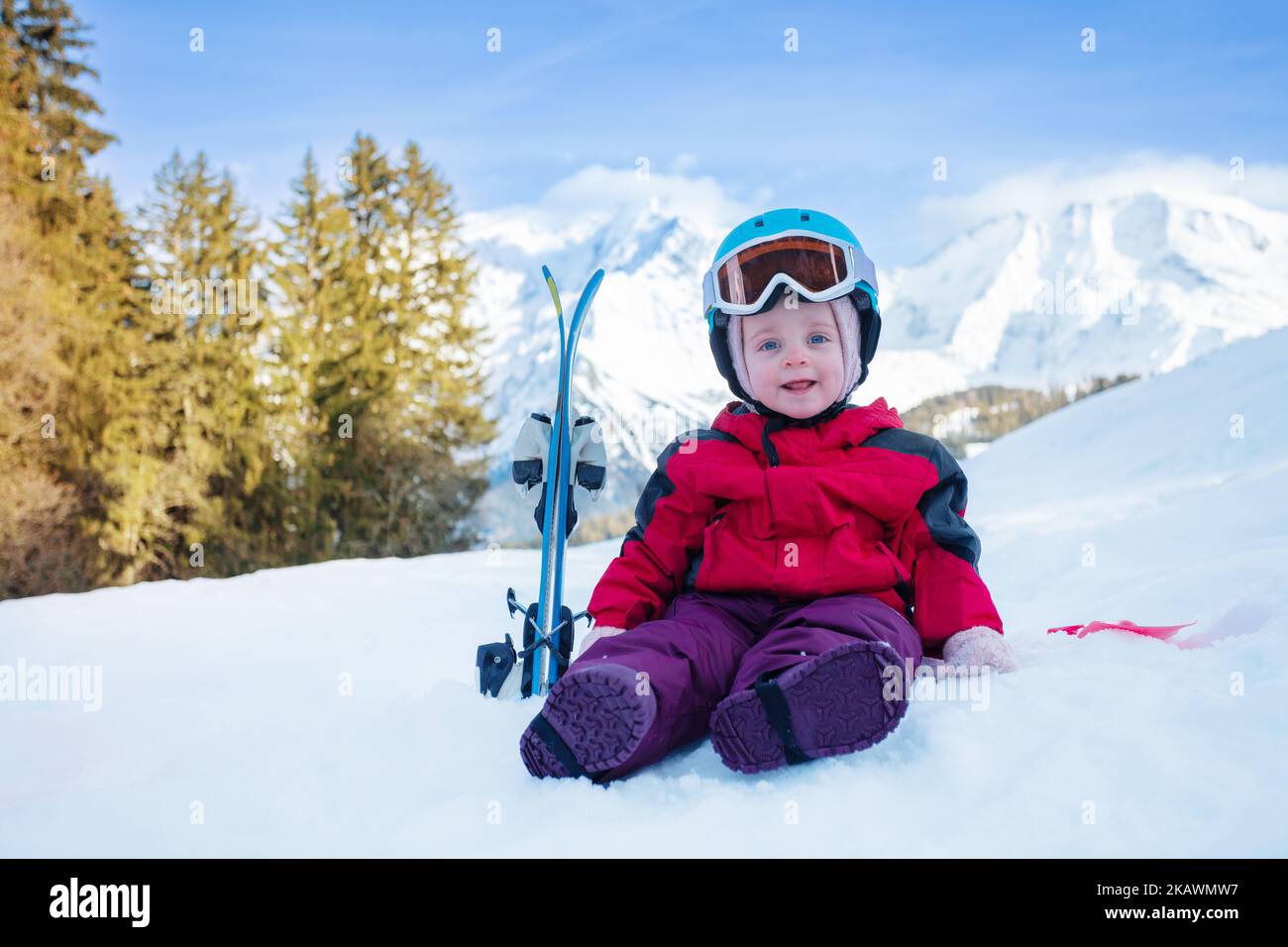 Little girl sit on snow with mountain ski in sport outfit Stock Photo