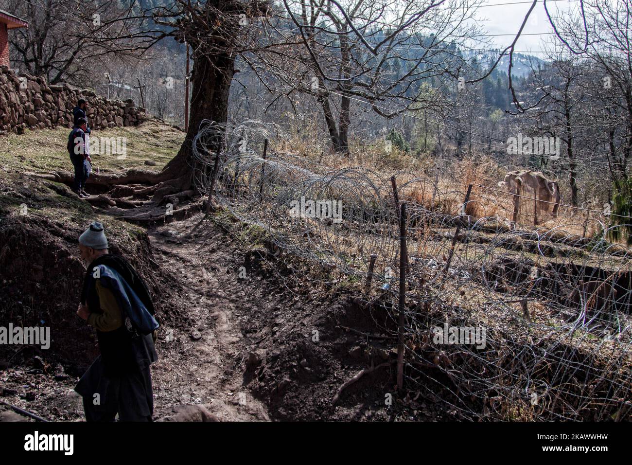 URI, KASHMIR, INDIA - FEBRUARY 27: Kashmiri men walk in front the bunker of Indian army as they walk towards their abandoned home during a fresh skirmish along the border on February 27, 2018 in Uri, 120 Kms (75 miles) north west of Srinagar , the summer capital of Indian administered Kashmir, India. The village with a population of a little over 12,000 has been bearing the brunt of cross-fire between nuclear rivals India and Pakistan. People living along the ceasefire line dividing Kashmir into India and Pakistan-administered portions have continually been at risk due to hostility between the Stock Photo