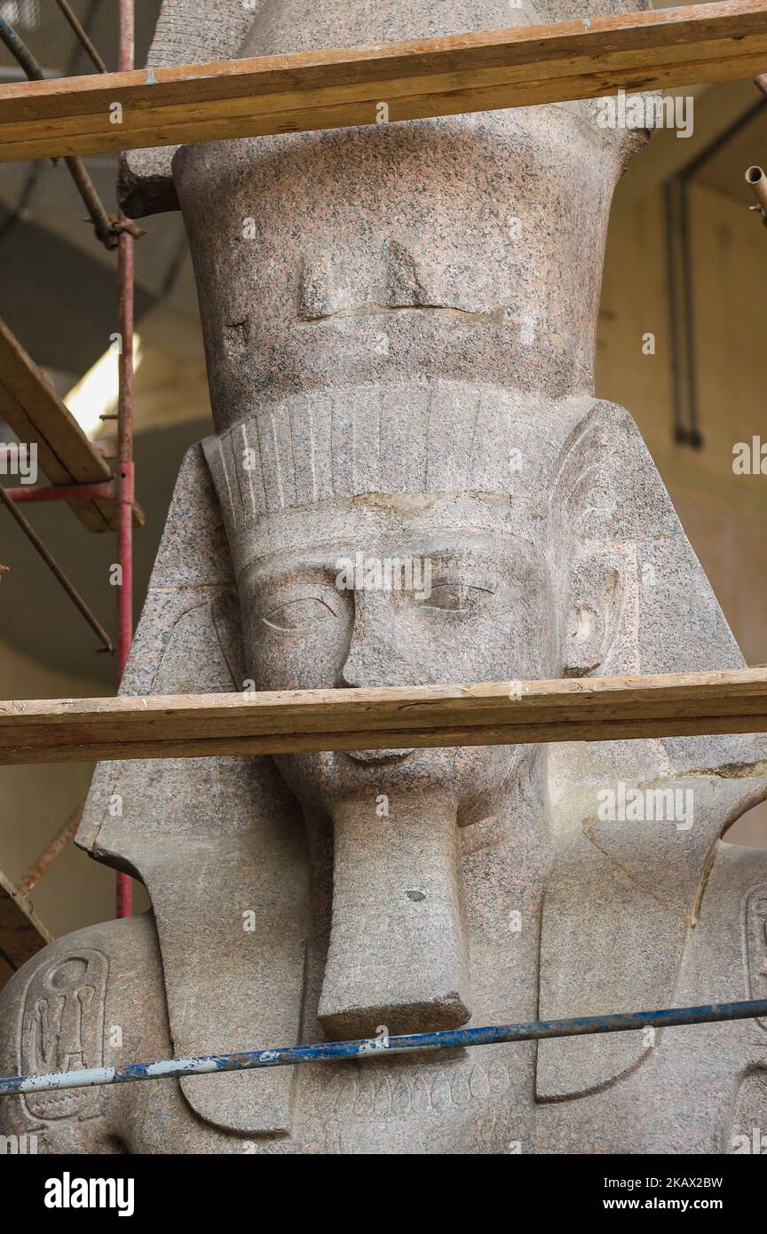 Egyptian workers restore a giant granite statue of the ancient Egyptian
