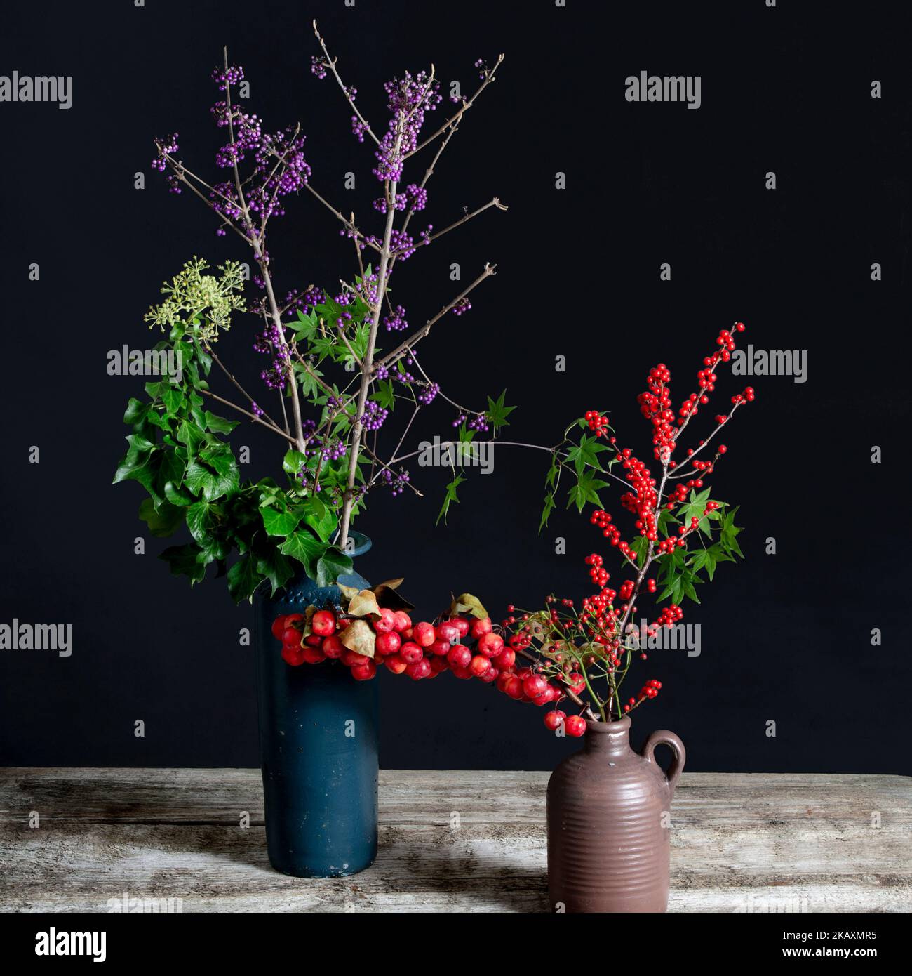 Callicarpa and Hedera helix and Ilex in blue and brown vases. Stock Photo