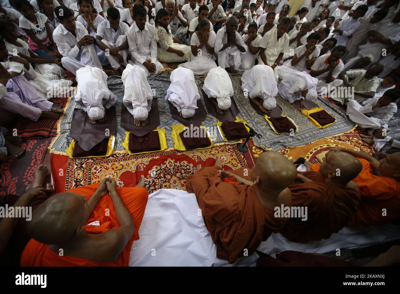 Sri Lankan boys dressed in white cloths worship the Sri Lankan Buddhist monks during a ceremony to be ordained as novice Buddhist monks (samanera) in Colombo, Sri Lanka on Sunday 29 April 2018 which also marks the Vesak full moon poya day Celebrated by Buddhists to mark three momentous events in Lord Buddha's life – his birth, enlightenment, and his departure from the human world. (Photo by Tharaka Basnayaka/NurPhoto) Stock Photo