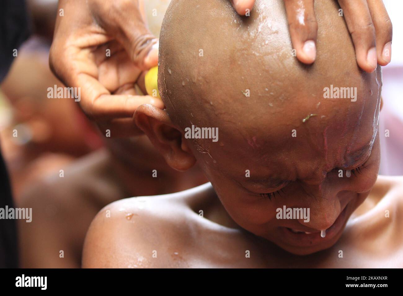 A Sri Lankan boy reacts as his shaved-head is applied with Lime by a Buddhist monk in preparation for a ceremony to be ordained as novice Buddhist monks (samanera) in Colombo, Sri Lanka on Sunday 29 April 2018 which also marks the Vesak full moon poya day, celebrated by Buddhists to mark three momentous events in Lord Buddha's life – his birth, enlightenment, and his departure from the human world. (Photo by Tharaka Basnayaka/NurPhoto) Stock Photo