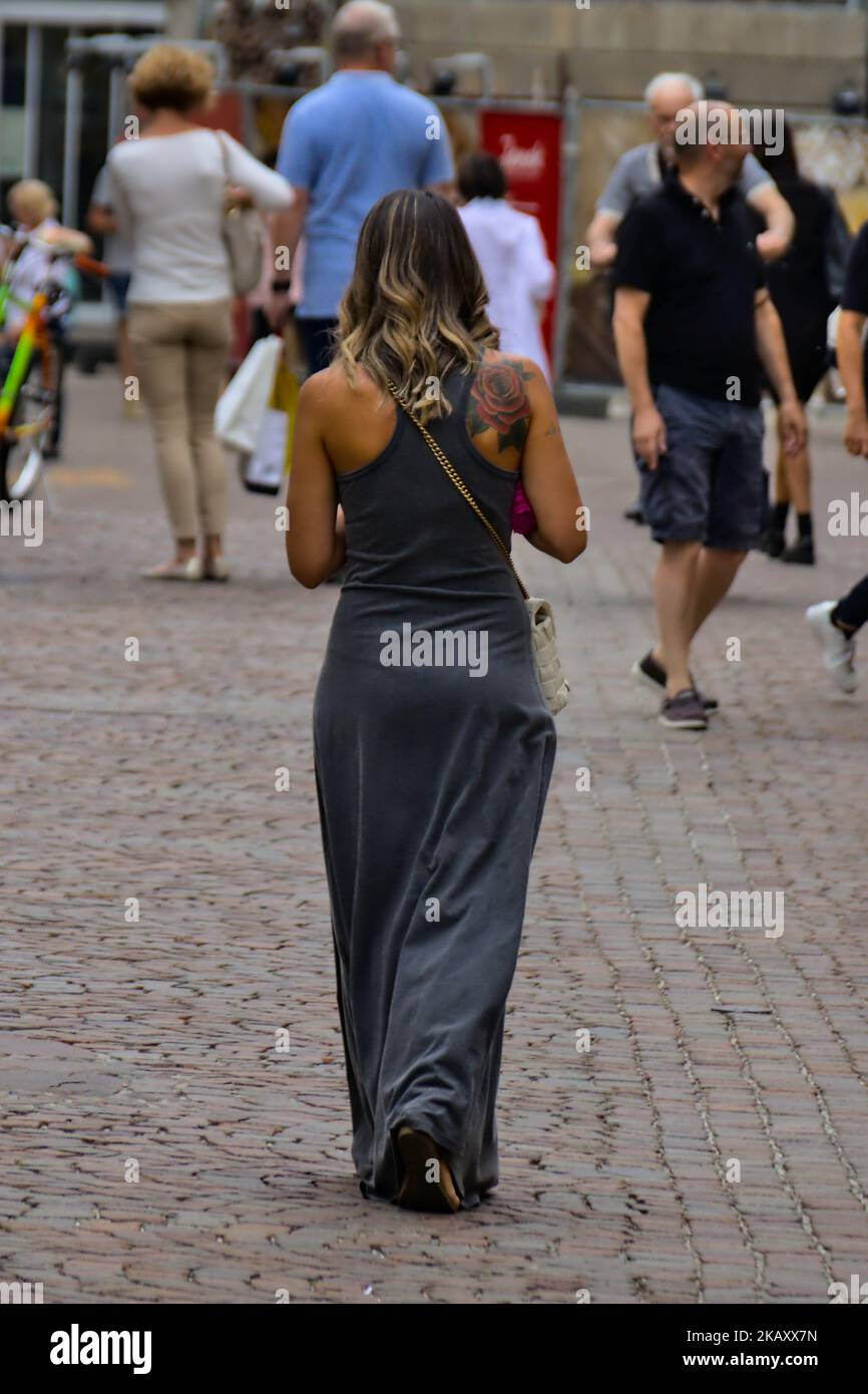 The vertical view of a woman with a Tattooed shoulder, walking on an urban street Stock Photo