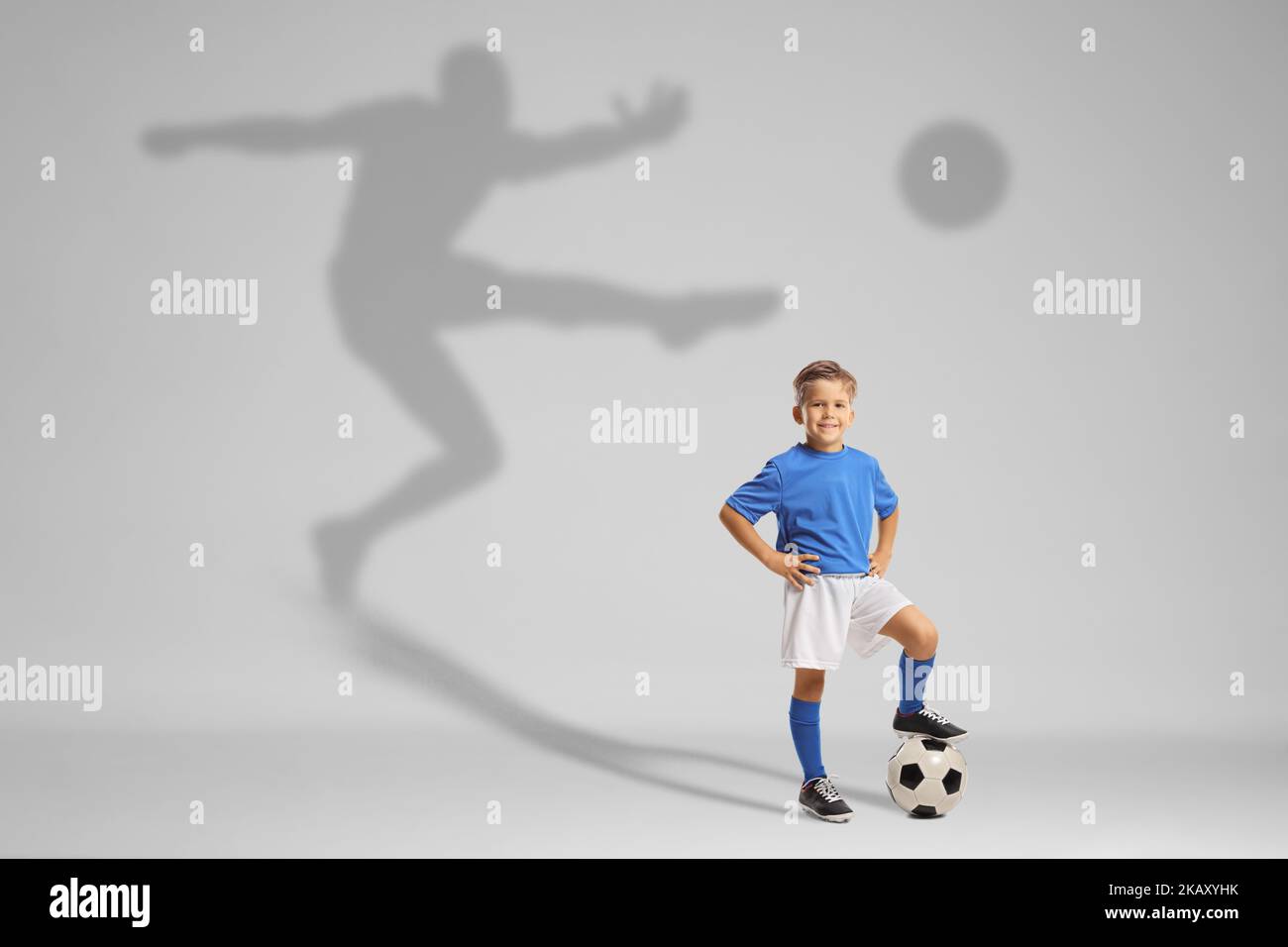 Boy in a football jersey thinking of becoming a famous football player with a shadow behind Stock Photo