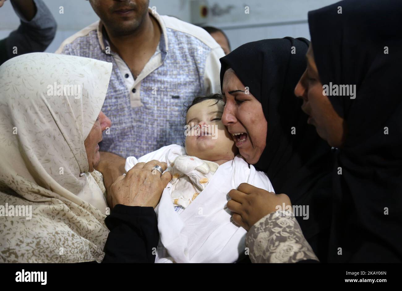 The mother of a Leila al-Ghandour (C), a Palestinian baby of 8 months who according to the Palestinian health ministry died of tear gas inhalation during clashes in East Gaza the previous day, holds her at the morgue of al-Shifa hospital in Gaza City on May 15, 2018 Fresh protests are expected a day after Israeli forces killed 59 Palestinians during clashes and protests along the Gaza border against the US embassy opening in Jerusalem in the conflict's bloodiest day in years. (Photo by Majdi Fathi/NurPhoto) Stock Photo